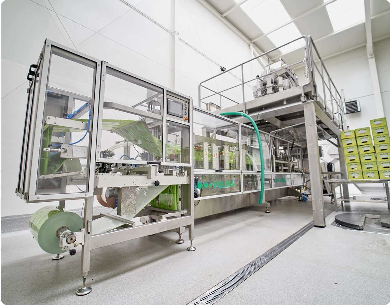 Obok widać nowoczesny proces produkcyjny w fabryce, z maszynami wykonującymi skomplikowane czynności.