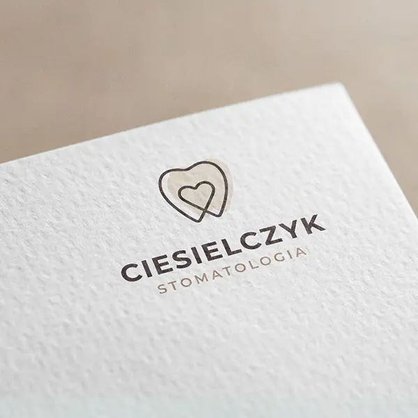 To logo zawiera subtelny motyw serca w kształcie zęba, które nawiązuje do branży stomatologicznej, reprezentując opiekę nad zdrowiem jamy ustnej.
