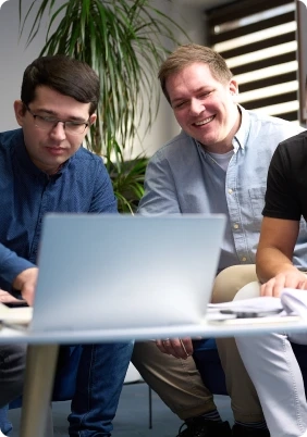 Zdjęcie przedstawia dwóch pracowników pracujących przy laptopie