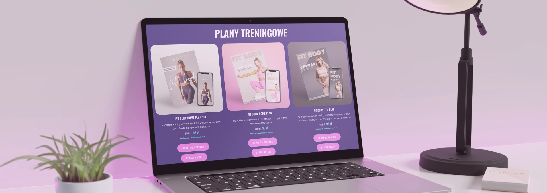 Laptop na pastelowym biurku wyświetla stronę z planami treningowymi, oferując trzy programy: FIT BODY HOME PLAN 3.0, FIT BODY HOME PLAN i FIT BODY GYM PLAN.