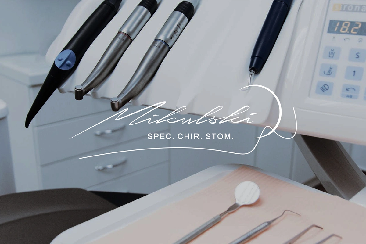 Logo Mikulski na tle sprzętu dentystycznego. Elegancka, odręczna czcionka z dopiskiem "SPEC. CHIR. STOM.", wskazującym na specjalizację w chirurgii stomatologicznej.