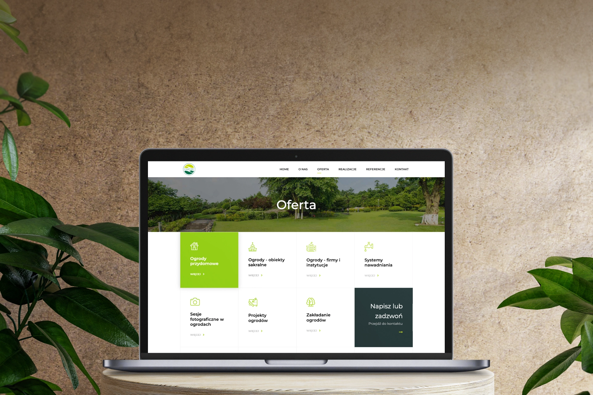 Na zdjęciu widoczna jest strona internetowa firmy oferującej usługi projektowania ogrodów. W sekcji "Oferta" znajdują się trzy główne kategorie: ogrody przydomowe, ogrody sakralne oraz ogrody dla firm i instytucji, a także systemy nawadniania. W tle widoczny jest zadbany ogród.