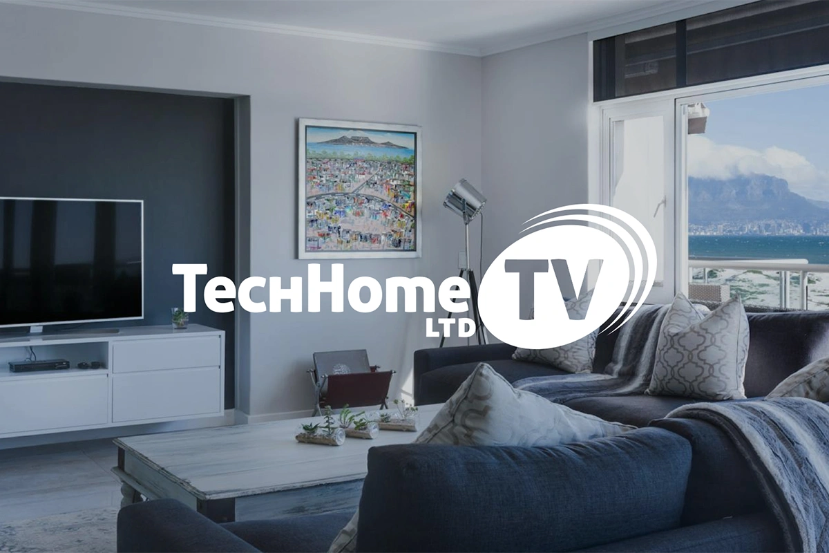 Logo "TechHome TV LTD" na tle nowoczesnego wnętrza z widokiem na ocean i góry. Stylowy design i dynamiczny symbol fal podkreślają technologiczny i medialny charakter marki.