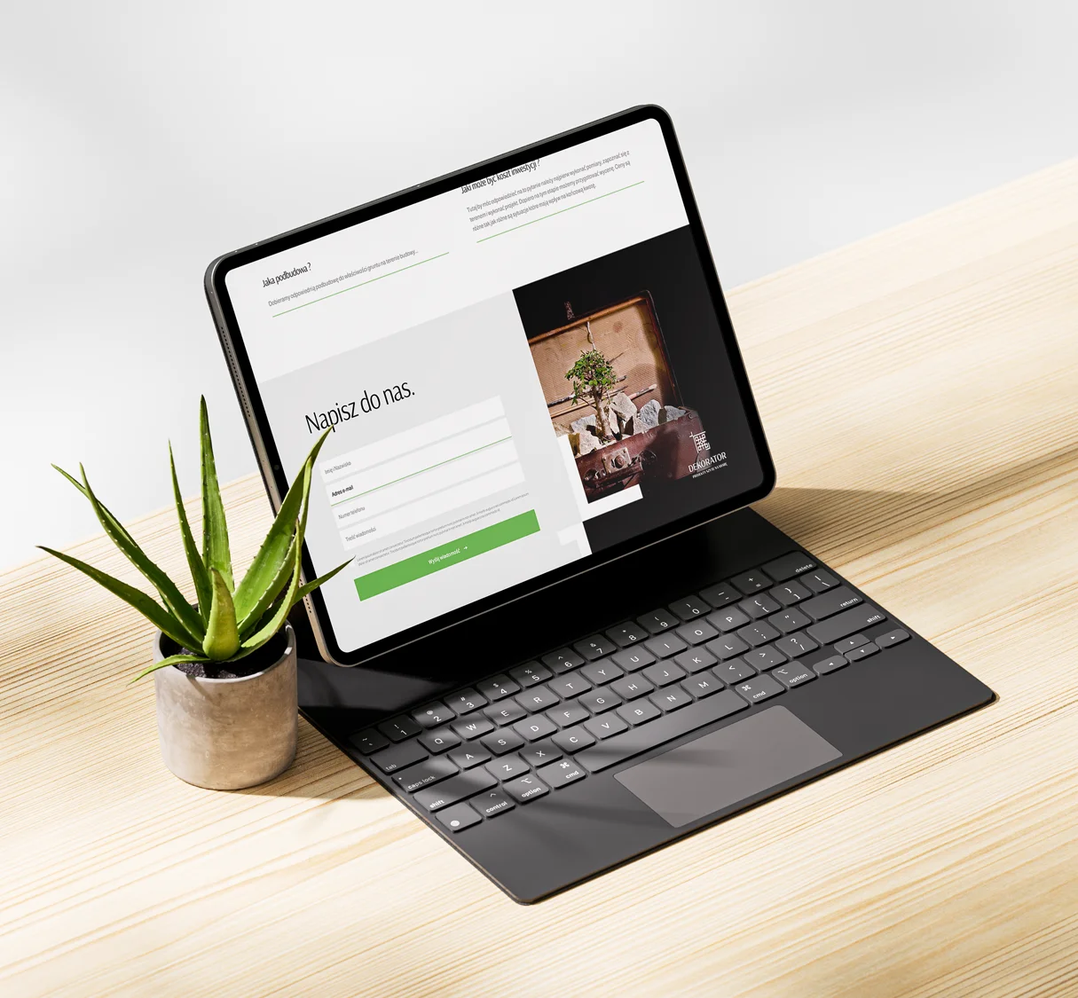 Obraz przedstawia nowoczesny tablet z klawiaturą, ustawiony na drewnianym biurku. Na ekranie widoczna jest strona internetowa z formularzem kontaktowym, zachęcającym do napisania wiadomości. Strona ma elegancki, minimalistyczny design z zielonymi akcentami, które nawiązują do natury..